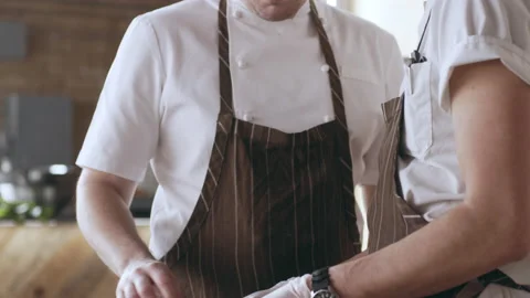 Chef telling his assistant how to cut the piece of veal in interior kitchen with Stock Footage 199458487