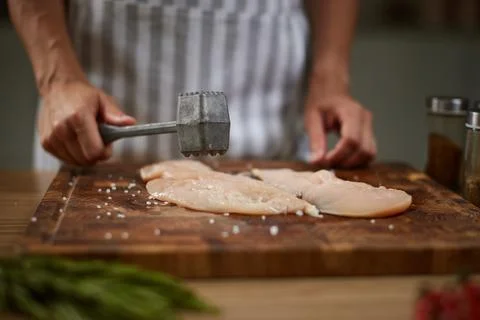 Chef tenderizing raw chicken breast with meat mallet Stock Photos