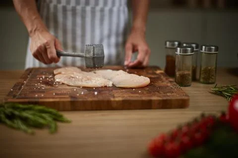 Chef tenderizing raw chicken breast with mallet Stock Photos