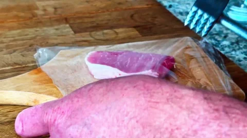 Chef tenderizing raw pork loin chop with a meat mallet Stock Footage 332431341