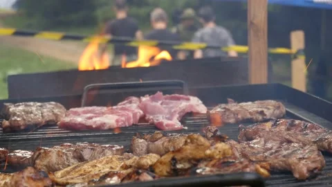 Chef throwing pieces of meat on a grill to fry and then serve to people wait Stock Footage 145483346