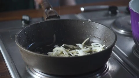 Chef throws chopped onions in a pan standing on the stove at kitchen restaurant. Vidéo 124709631