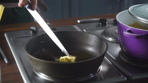 Chef throws piece of butter on a hot frying pan standing on stove at kitchen. Vidéo 124709511