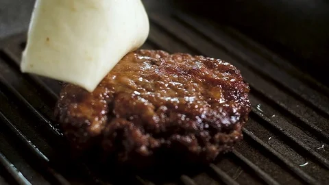 Chef throws piece of melted cheese on cutlet in pan. camera moves back, forth Stock Footage 111761177