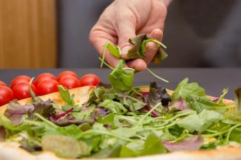 The chef throws the pizza with slices of lettuce and fresh herbs , pizza cooking Stock Photos