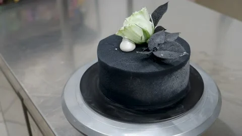 Chef topping black airbrush painted frosted icing cake on top two real rose.. Vidéo 236571237