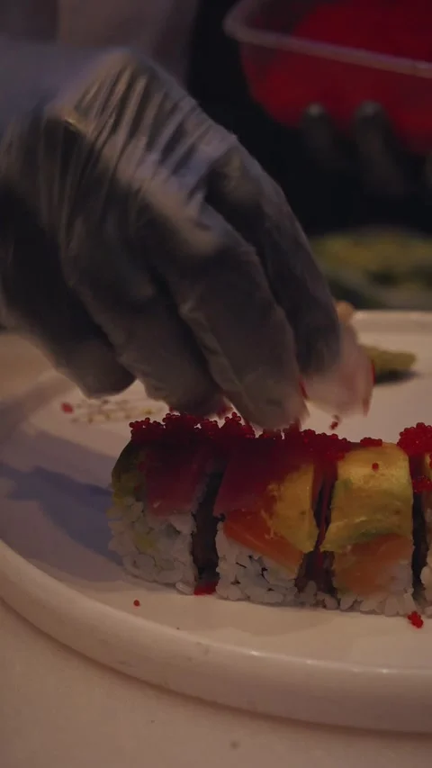 Chef topping rainbow sushi rolls with orange tobiko – 4K vertical video Stock Footage 315419176