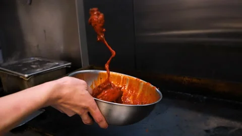 Chef tosses fried chicken wings in vibrant orange buffalo sauce, slow Stock Footage 199602164