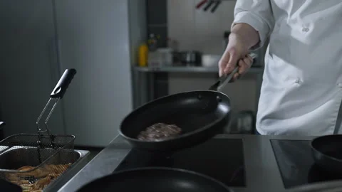 Chef tosses roasting beef on the hot pan at the restaurant kitchen in slow mo Stock Footage 143780015