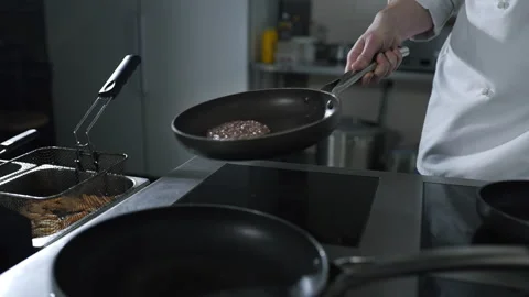 Chef tosses roasting beef on the hot pan at the restaurant kitchen Stock Footage 143780087