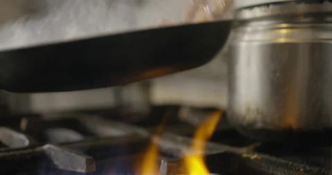 Chef tosses squid in frying pan over flame grill Stock Footage 274653778