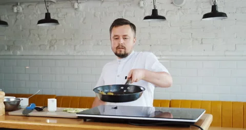 Chef tossing throws up burning with fire vegetables on frying pan. Mixing pieces Stock Footage 132967030