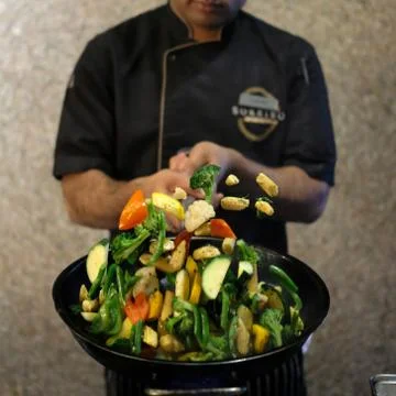 A chef tossing vegetables in a pan Stock Photos