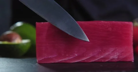 Chef touches fresh piece of raw tuna with sharp knife. Cooking sushi, sashimi Stock Footage 148765936