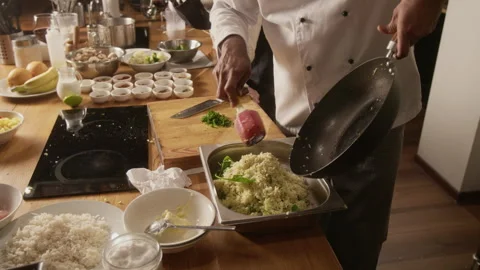 Chef Transferring Dish from Wok Into Container During Cooking Master Class Stock Footage 332574451