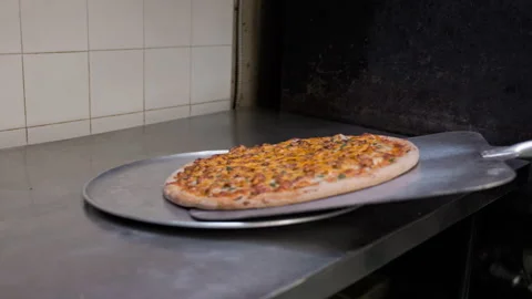 Chef Transferring Pizza from Peel to Pan – Freshly Baked Pizza Preparation 動画素材 303205241