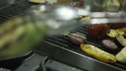 The chef transfers the roasted vegetables from the grill to a large container Stock Footage 243436962