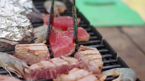 A chef tries to lift a grilled piece of tuna off the grill to turn it over. 库存影片 313300053