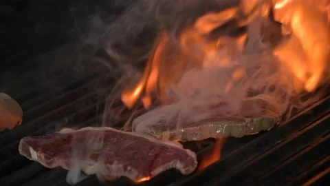 Chef turning meat on the grill. The fire is burning in slow motion. Stock Footage 148238056