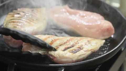 The chef turns the chicken breasts in a grill pan. Stock Footage 198533717