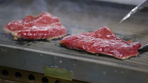 The chef turns the grilled meat over with tongs. Close-up Video stock 130903746