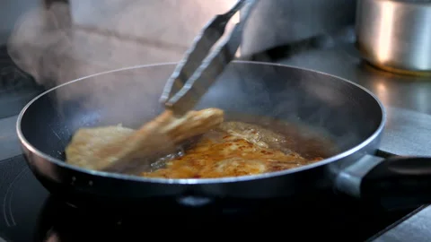 Chef turns over maet eith cooking tongs. Meat is frying in the pan Video stock 132413610