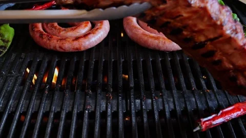 Chef turns over pork ribs On Grill. Cooking  sausage on grill. Slow motion. Stock Footage 274485449