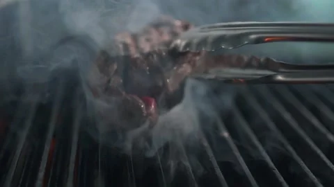 Chef turns over the roasting beef steak over smoke and fire Stock Footage 143780181