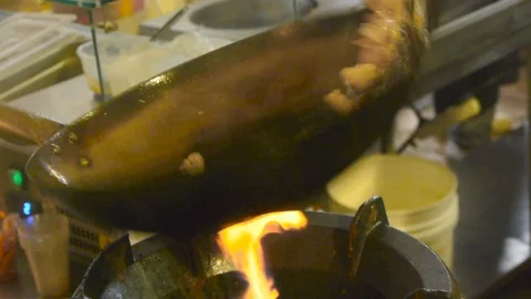 The chef turns over small pieces of meat in a frying pan wok over a gas burner Stock Footage 84252248