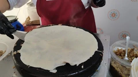 Chef turns thin pancake over in hot pan using special spatula. Process of frying Stockbeeldmateriaal 317948283