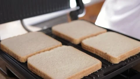 Chef in uniform closing an electric grill filled with six slices of bread, .. Video stock 293716758