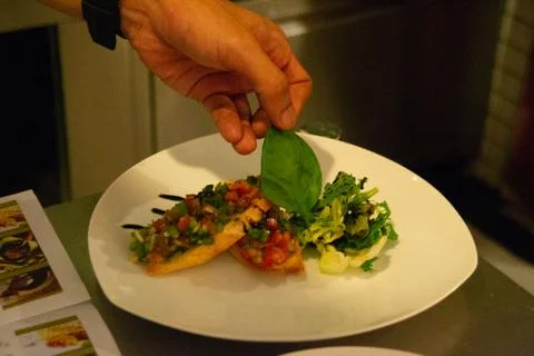 Chef in uniform in kitchen preparing buchetta and chikcen piccata Stock Photos