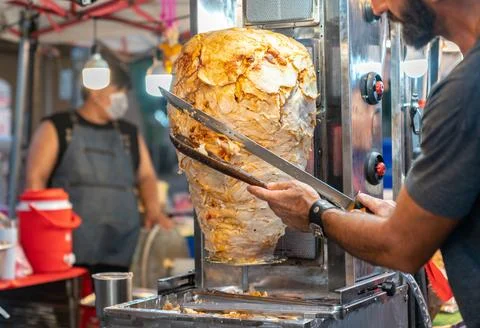 Chef use long sword slice meat on vertical grill for made kebub. Stock Photos