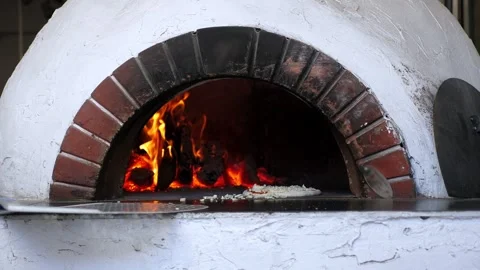 The chef used a spatula to place pizza in a wood-burning oven. Stock Footage 307394590