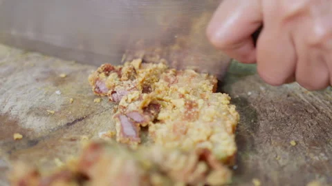 Chef uses a cleaver to chop crispy fried pork belly on a wooden cutting board Video stock 336500441