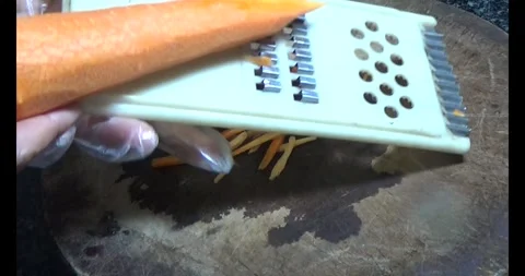 The chef uses a grater to grate carrots into long strips Stock Footage 308361602