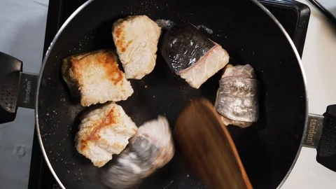 Chef uses his spatula to tip over fish bites.Process of cooking fish in a Stock Footage 112346757