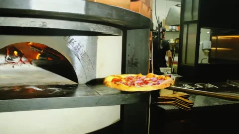 Chef uses specialized pizza peel to remove pizza from hot oven Stock Footage 326370714
