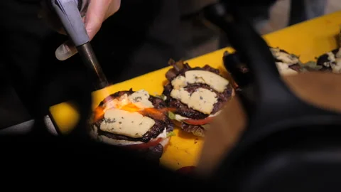 Chef using blow torch to melt cheese on burger Stock Footage 143318569