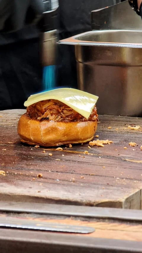 Chef using blowtorch to melt cheese on pulled pork sandwich Video stock 335637800