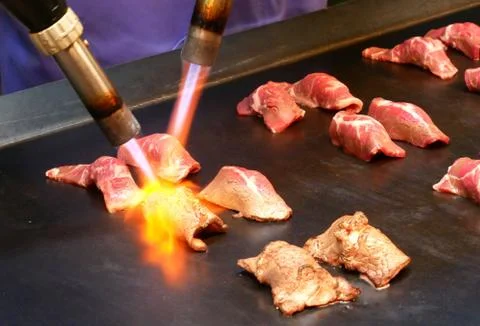 Chef using burnt torch prepares sushi. Stock Photos