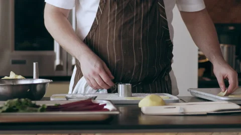 Chef using a circular ring to cut pieces of potatoes in interior kitchen with so Stock Footage 199459639