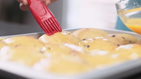 Chef using culinary brush to apply egg on Easter traditional hot cross buns. Stock Footage 151046696