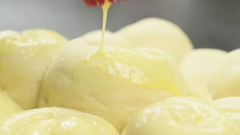 Chef using culinary brush to apply broken egg on bread rolls, before baking. Stock Footage 159907859