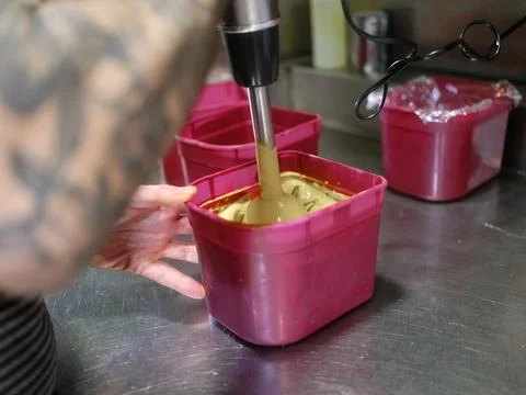 Chef using an electric mixer to remove sauce in a plastic container in a Stock Photos