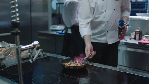 Chef using a flame to cook food in the pan Stock Footage 283012435