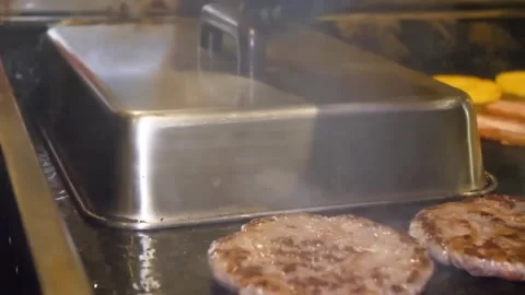 Chef Using Griddle Basting Cover Over Burger Patties on Flat Top Grill Stock Footage 347687634