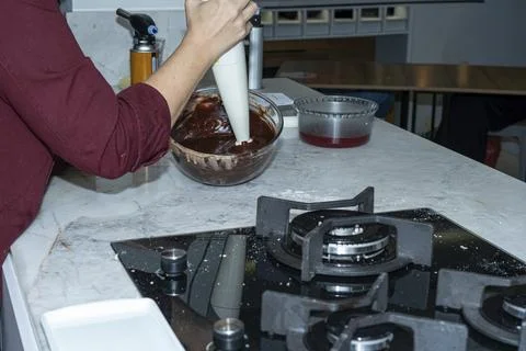 Chef using a hand mixer on the chocolate filling to make it more fluid. Stock Photos