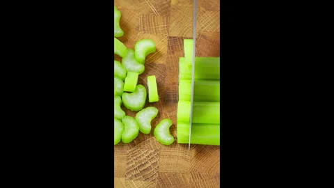 Chef using kitchen knife to slice celery stalks on wooden board. Video stock 302634069