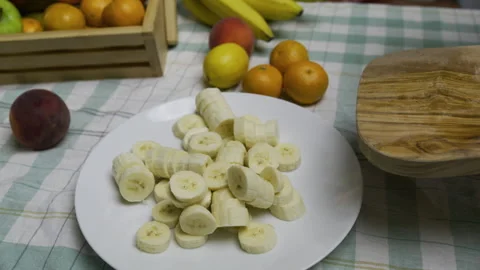 Chef using knife to push banana slices off cutting board and onto plate - slow Stock Footage 341196791